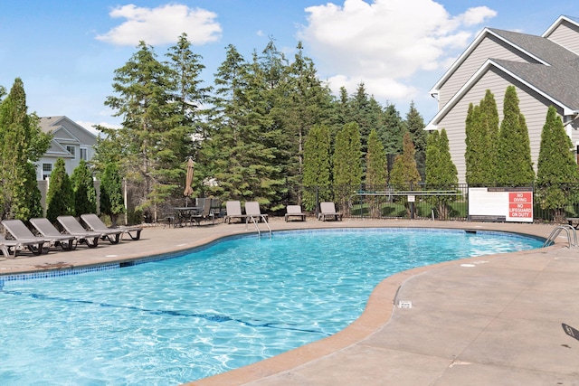 pool with a patio area and fence