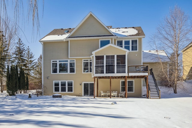 snow covered house with a sunroom and stairs