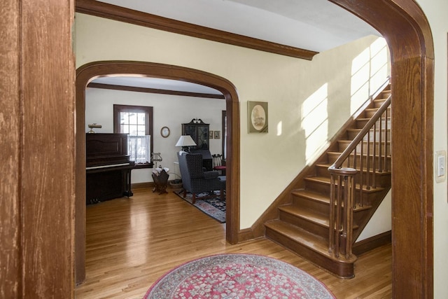 interior space with arched walkways, beam ceiling, baseboards, and wood finished floors