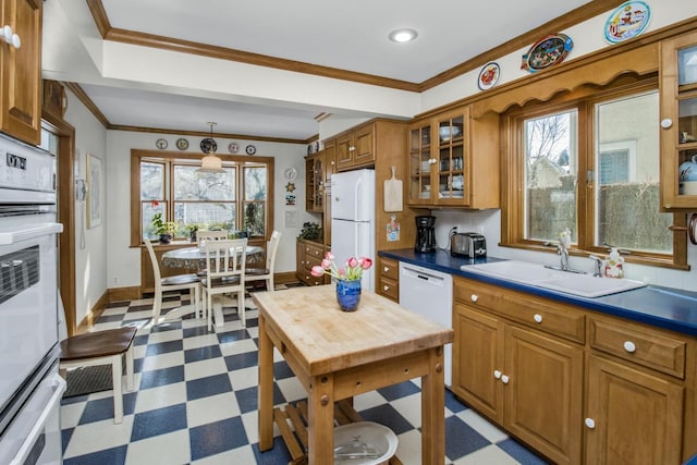 kitchen with dark countertops, white appliances, glass insert cabinets, and brown cabinets