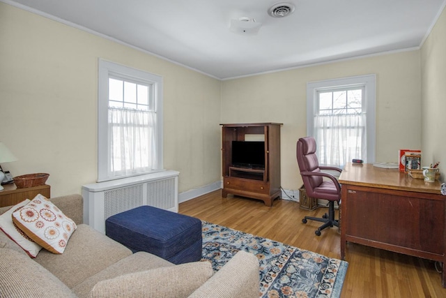 office area featuring radiator, light wood-type flooring, visible vents, and crown molding