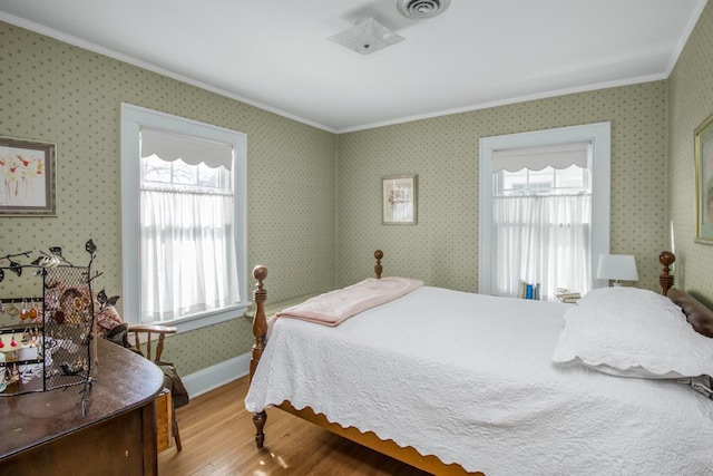 bedroom with visible vents, multiple windows, light wood-style flooring, and wallpapered walls