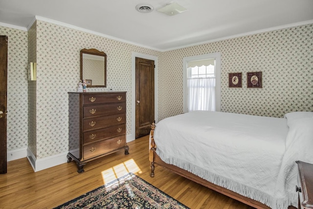 bedroom with wallpapered walls, visible vents, crown molding, and wood finished floors