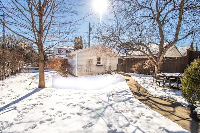 yard covered in snow featuring fence and an outbuilding