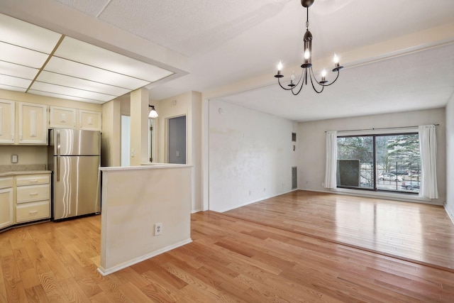 kitchen with pendant lighting, stainless steel fridge, light wood-type flooring, and an inviting chandelier