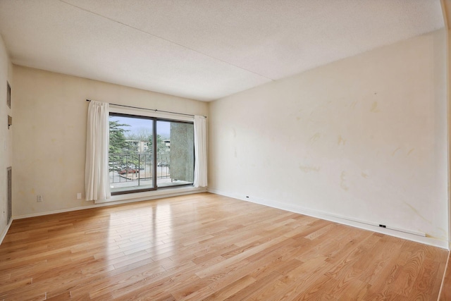 spare room featuring light wood-type flooring and a textured ceiling