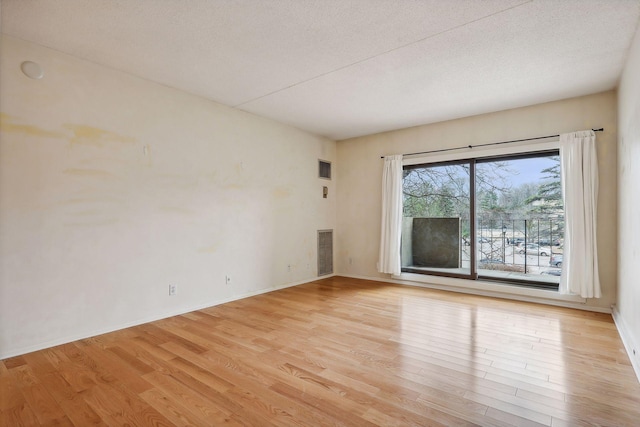 spare room featuring a textured ceiling and light wood-type flooring