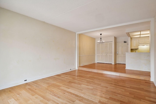 unfurnished room featuring a chandelier and light hardwood / wood-style flooring