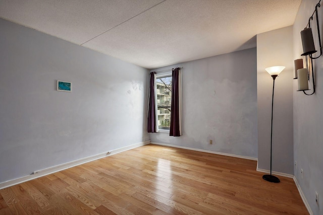 unfurnished room featuring a textured ceiling and light hardwood / wood-style floors