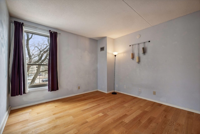 spare room featuring light hardwood / wood-style floors and a textured ceiling