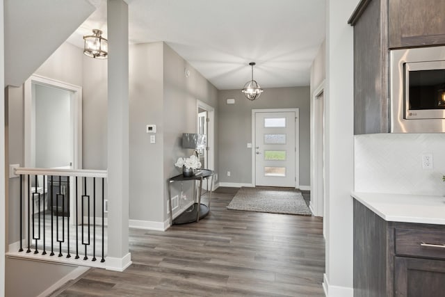 foyer featuring an inviting chandelier, baseboards, and dark wood-style flooring