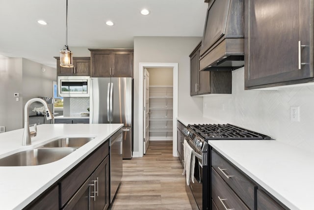 kitchen with stainless steel appliances, light countertops, decorative light fixtures, and a sink