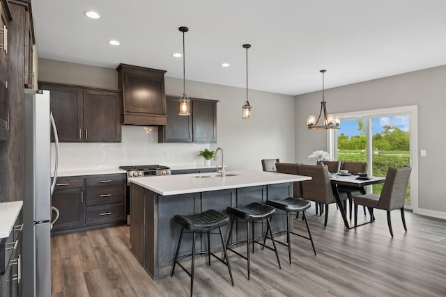 kitchen featuring premium range hood, a sink, light countertops, appliances with stainless steel finishes, and decorative light fixtures