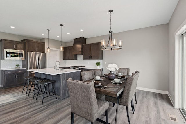 dining space with light wood finished floors, baseboards, a notable chandelier, and recessed lighting