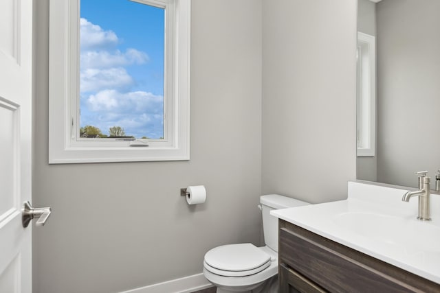 bathroom with toilet, baseboards, and vanity