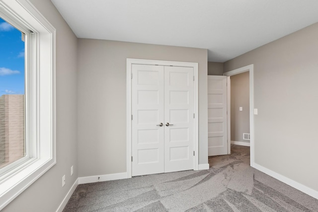 unfurnished bedroom featuring light carpet, visible vents, baseboards, and a closet