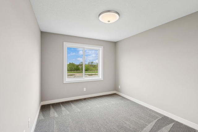 carpeted spare room featuring baseboards