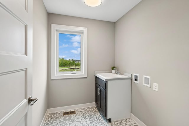 laundry room featuring washer hookup, cabinet space, a sink, and baseboards