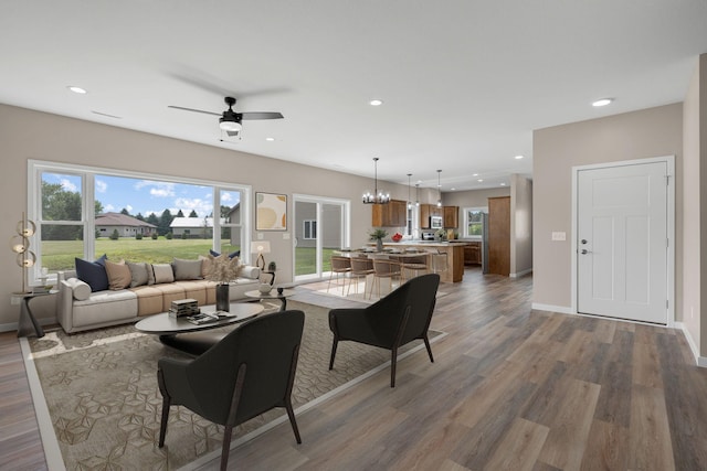 living area featuring recessed lighting, baseboards, wood finished floors, and ceiling fan with notable chandelier