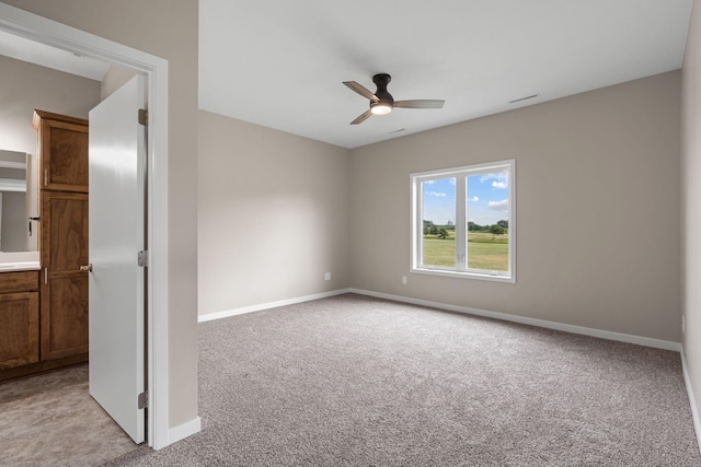 unfurnished room featuring baseboards, light colored carpet, and a ceiling fan