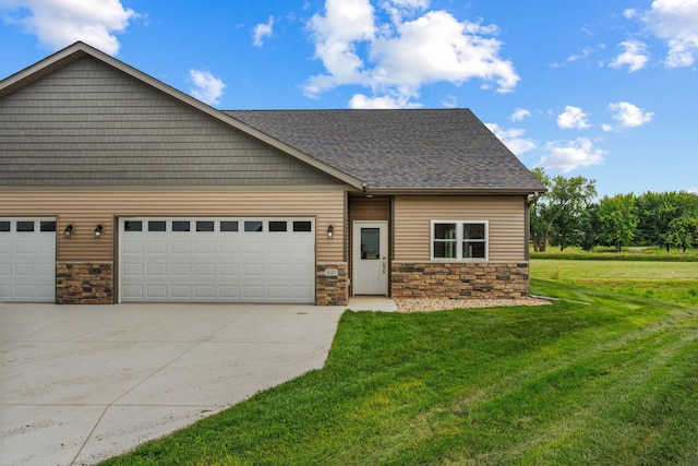 view of front of house with a shingled roof, a front lawn, driveway, stone siding, and an attached garage