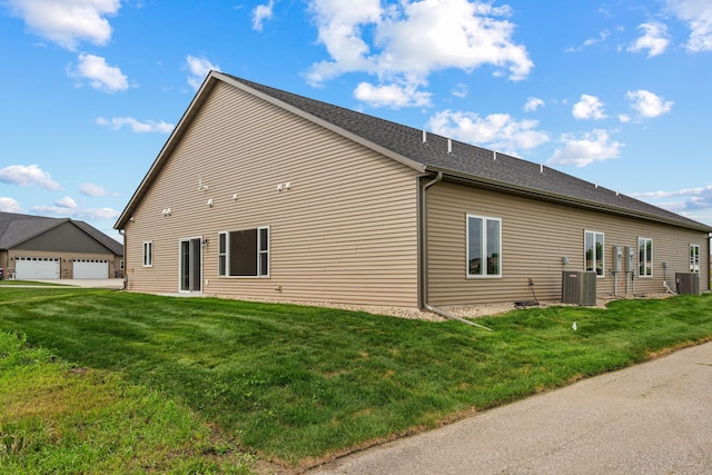 view of side of property with central air condition unit, a lawn, and a garage