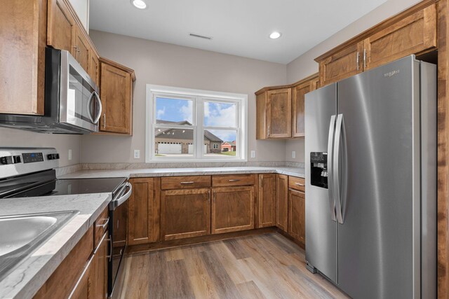 kitchen featuring recessed lighting, brown cabinets, stainless steel appliances, and light wood-style floors