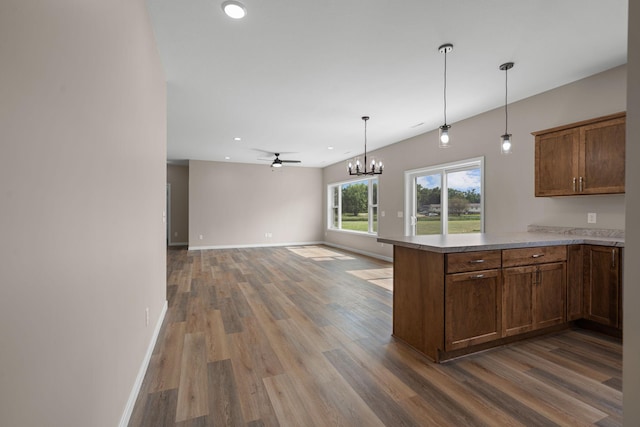 kitchen featuring baseboards, a peninsula, wood finished floors, and hanging light fixtures