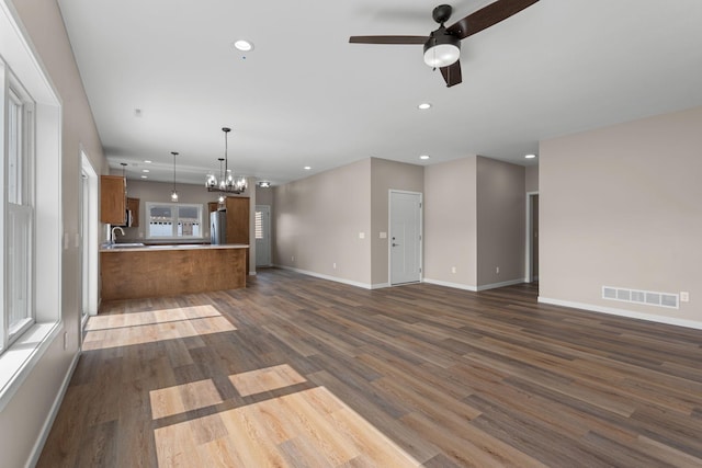 unfurnished living room featuring visible vents, baseboards, recessed lighting, dark wood-type flooring, and ceiling fan with notable chandelier