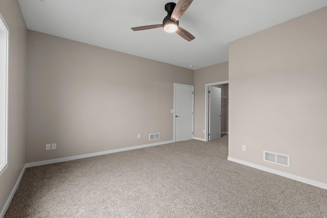 empty room with carpet flooring, baseboards, visible vents, and ceiling fan