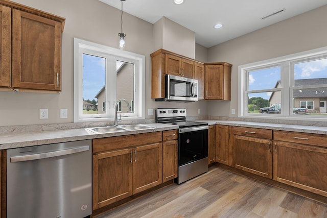 kitchen with visible vents, a sink, light wood-style floors, appliances with stainless steel finishes, and brown cabinets