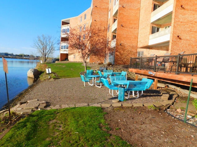 surrounding community with a deck with water view and a yard