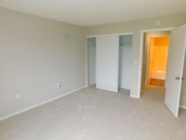 unfurnished bedroom featuring light carpet and a closet