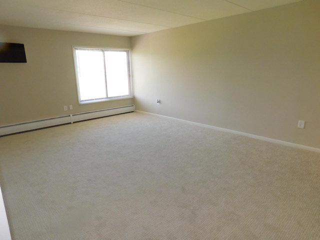 spare room featuring light colored carpet and a baseboard heating unit