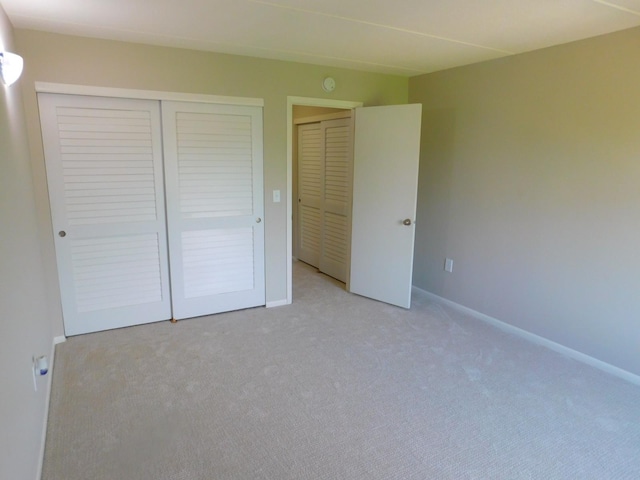 unfurnished bedroom with light carpet and a closet