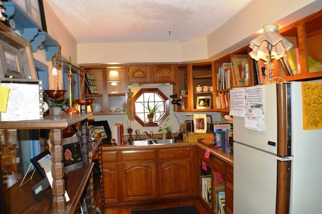 kitchen with white fridge, a textured ceiling, sink, a chandelier, and dark hardwood / wood-style floors