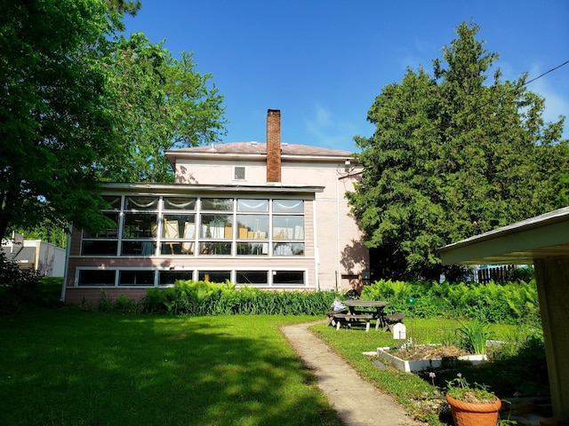 rear view of house with a yard and a sunroom