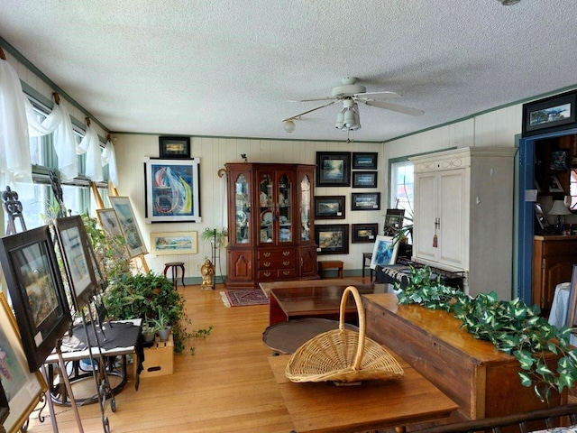 dining space with ceiling fan, a textured ceiling, and light wood-type flooring