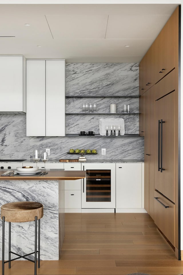 bar with light hardwood / wood-style floors, white cabinetry, backsplash, and wine cooler