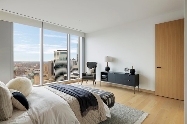 bedroom with light hardwood / wood-style flooring and a wall of windows