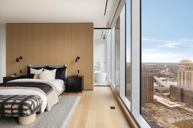 bedroom featuring light wood-type flooring, multiple windows, and wooden walls