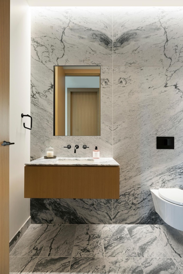 bathroom featuring vanity, tile walls, and toilet