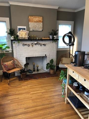 living room featuring a brick fireplace, light wood-type flooring, and crown molding