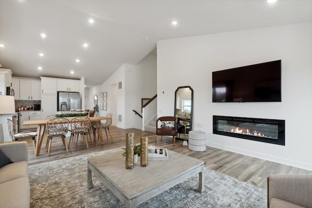 living room with light hardwood / wood-style floors and high vaulted ceiling