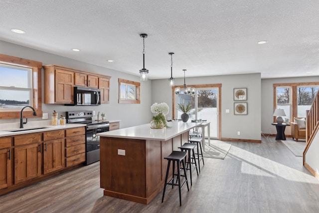 kitchen with a kitchen island, pendant lighting, sink, a kitchen breakfast bar, and stainless steel appliances