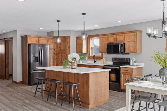 kitchen featuring decorative light fixtures, a barn door, stainless steel fridge with ice dispenser, and black / electric stove