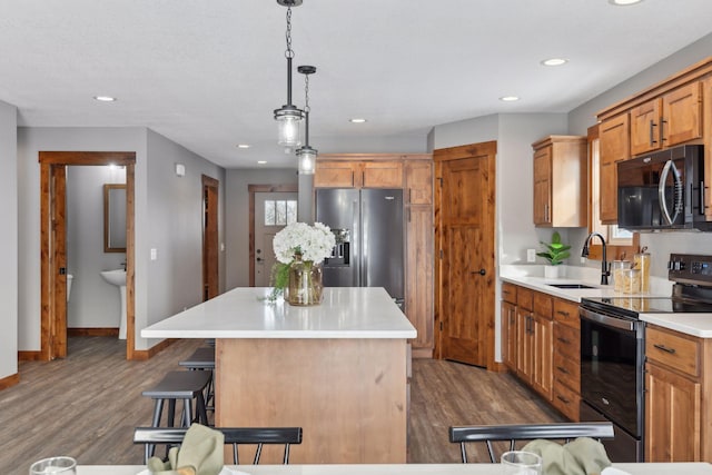 kitchen with sink, stainless steel appliances, a center island, a kitchen bar, and decorative light fixtures