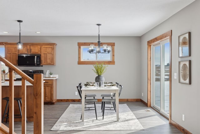 dining area with plenty of natural light, a notable chandelier, and dark hardwood / wood-style flooring