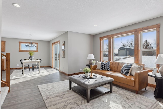 living room featuring an inviting chandelier, light hardwood / wood-style floors, and a textured ceiling