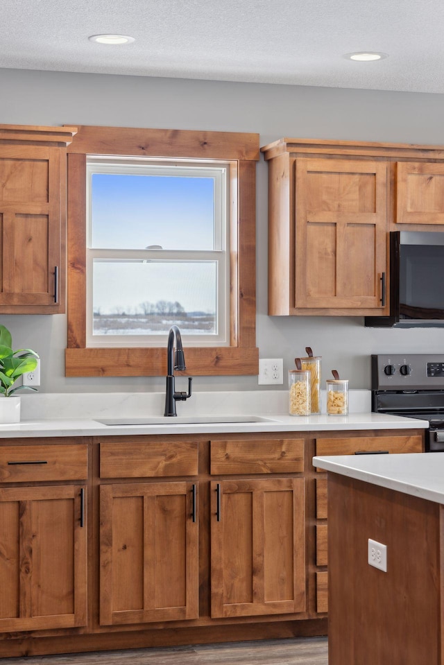 kitchen with stainless steel range with electric stovetop, sink, and a textured ceiling